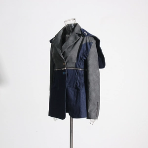Gros plan du col asymétrique et du zip sur la veste en daim gris et denim bleu