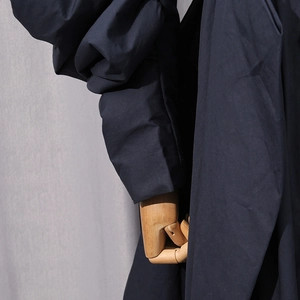 Detailed macro view of navy blue trench coat sleeve with oversized lantern cuff design