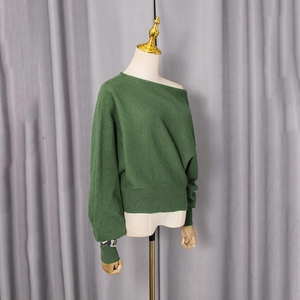 Detail of dark green off-shoulder knit sweater with soft texture and batwing sleeves