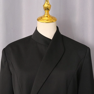 Detail of black blazer featuring an asymmetric crossover collar and premium fabric texture