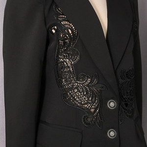 Detailed close-up of intricate black lace appliqué and silver buttons on a black blazer