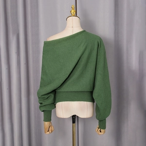 Macro detail of dark green knit sweater showing the wide ribbed hem and soft fabric texture