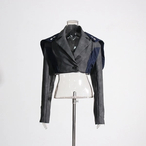 Détail du blazer court gris avec patchwork en denim, clous argentés et éléments zippés