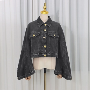 Detail of charcoal black washed denim jacket with large flare sleeves and gold embossed buttons
