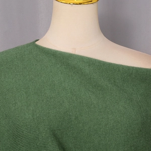 Close-up of the forest green fine knit fabric and elegant off-shoulder neckline design