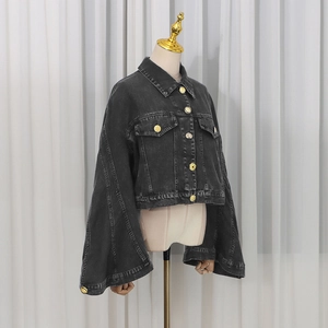 Detail of dark grey washed denim jacket featuring wide cape sleeves and golden buttons