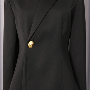 Detailed close-up of a black blazer featuring a unique artistic golden button on the waist