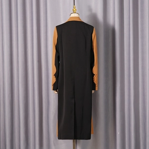 Detail view of the contrast color sleeves and back vent on the long black and tan blazer
