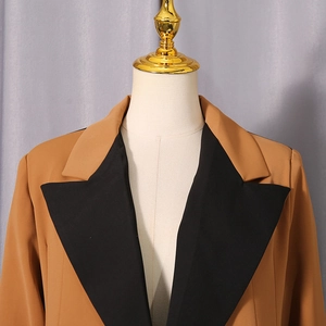 Detail shot of khaki blazer featuring a black contrast peak lapel and dense fabric
