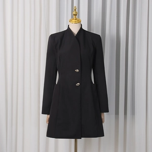 Détail d'une robe blazer noire avec des boutons dorés et un col montant structuré