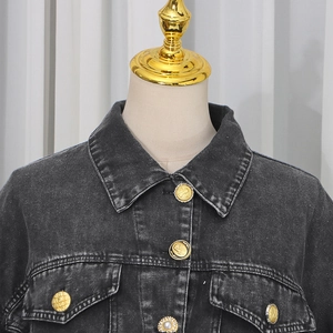 Detail of dark gray washed denim jacket with gold embossed buttons and pearl accent