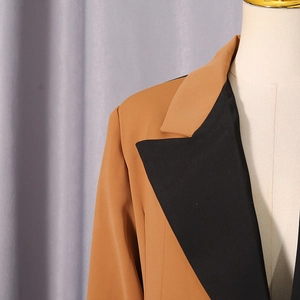 Detail of color-block blazer with camel body and black notched lapel for professional style