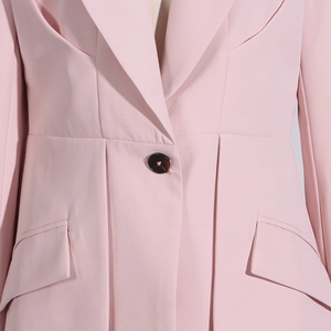 Detail of light pink blazer showing notch lapel, button closure and flap pocket design