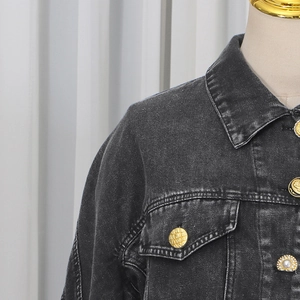 Detail of dark grey denim jacket featuring embossed gold buttons with pearl accents