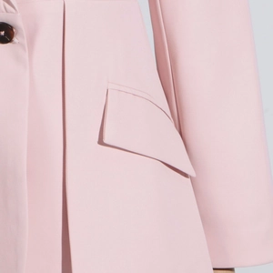 Detail of pink blazer flap pocket with fine stitching and textured brown button