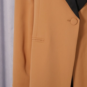 Detailed view of color-block lapels and matching button on a tailored blazer