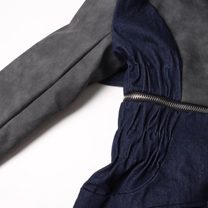 Détail d'une veste en jean tendance avec coutures en daim gris, plis et zip métallique