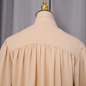 Detail view of the pleated back design and tie-neck collar on an apricot chiffon blouse