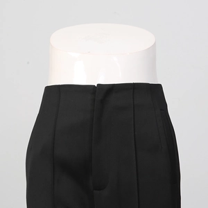 Detailed close-up of high-waisted black suit trousers showing stitching on a white mannequin