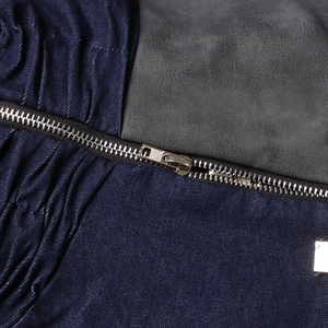 Détail de la fermeture éclair en métal et textures de tissus de la veste en jean