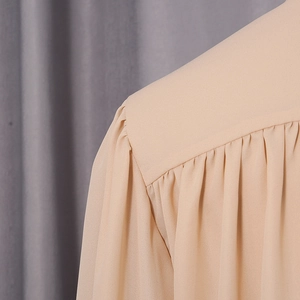 Detail shot of gathered shoulder stitching on a light beige chiffon blouse top