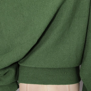 Close-up of forest green knit sweater showing fine ribbed hem and soft fabric texture