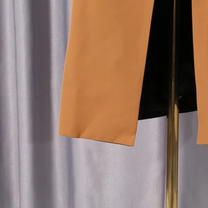 Detail view of khaki color-block blazer featuring sharp side slit and black inner lining