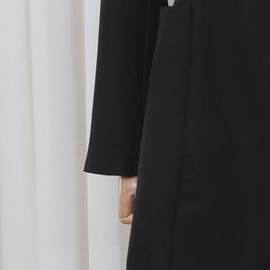 Détail macro de la texture du tissu tissé noir sur la manche et la poche d'une robe blazer