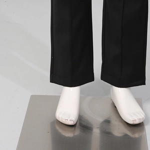 Detail of black straight-leg trousers with sharp center creases and fine hem stitching