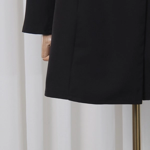 Détail de la couture sur l'ourlet et les poignets de cette robe blazer noire à manches longues