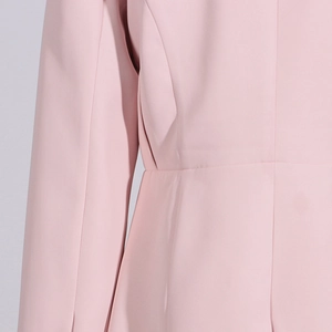 Detailed side view of pink blazer showing precise stitching and woven fabric texture