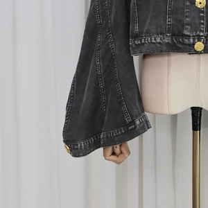 Detail of flared cuffs on washed grey denim jacket with vintage gold relief buttons