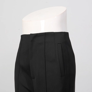 Detailed view of high-waisted black tailored trousers with vertical seam stitching details