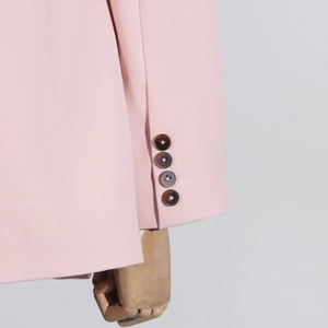 Detail of pink blazer sleeve featuring four dark marble texture buttons and fabric texture