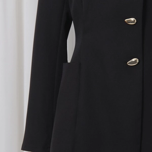 Détail du tissu noir de la veste avec des boutons dorés uniques en forme de goutte