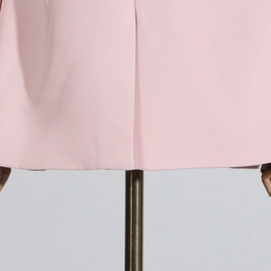 Detail view of the pink suit hem with diagonal twill texture and precision stitching