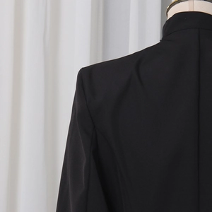 Gros plan des coutures structurées de l'épaule et du col sur une robe blazer noire