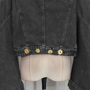 Detail of dark grey cropped denim jacket featuring vintage wash and gold embossed buttons