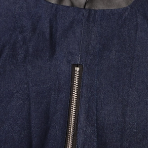 Détail de la fermeture éclair métallique sur une veste en jean bleu foncé avec cuir noir