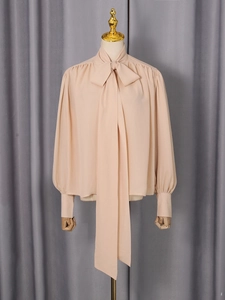 Elegant apricot long-sleeve blouse with oversized bow tie and puff sleeves on mannequin