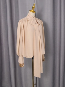 Elegant apricot long sleeve shirt with a pussy-bow neck and lantern sleeves on a mannequin