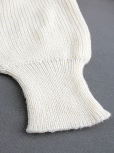 Gros plan des poignets en tricot côtelé blanc sur un cardigan long pour femme