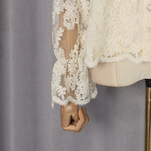 Gros plan détaillé du tissu en dentelle crème avec motifs floraux et bouton perle