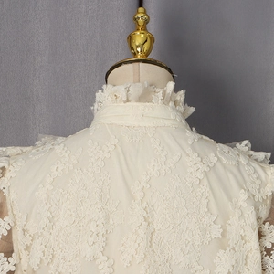 Détail d'un chemisier beige en dentelle avec broderies florales et col montant élégant
