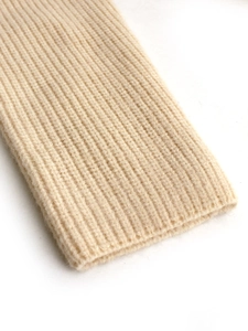 Macro shot of off-white rib-knit texture and soft sleeve cuff detailing on the sweater