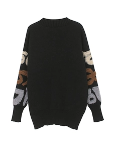 Détail d'un cardigan noir avec broderie bouclée 3D beige et marron sur les manches longues