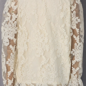 Détail d'un chemisier crème à manches longues avec dentelle au crochet et broderie florale