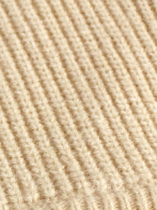 Detailed macro shot of premium beige ribbed knit fabric with soft wool texture