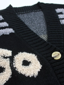 Gros plan d'un gilet en maille à col en V avec motifs de lettres et bouton marbré