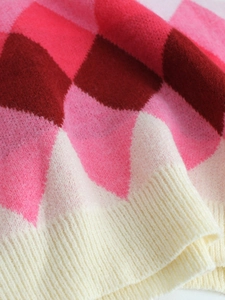 Detail of soft argyle knit sweater with red and pink diamonds and ribbed trim